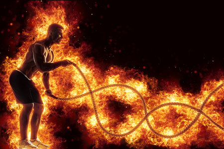 Muscular man working out with battle ropes. Flame backgroundの写真素材