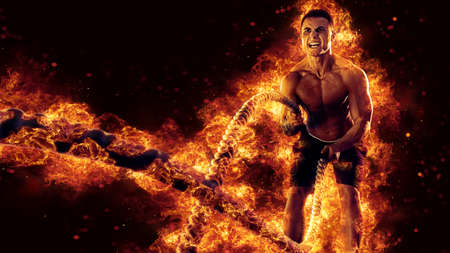 Muscular man working out with battle ropes. Flame backgroundの写真素材