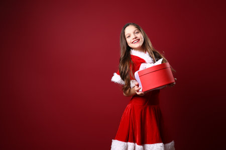 Beautiful little girl in festive costume hold gift box. christmas decoration. holiday. funの写真素材