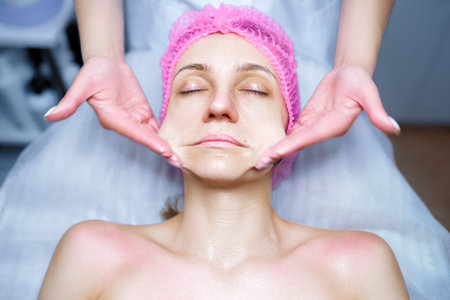Attractive female at spa health club getting a facial massage. Beautician doing massage of face, neck and shoulders ofbeautiful young woman at luxury beauty salonの写真素材