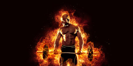 The shirtless abdominal male holds dumbbell. Studio shot in contrasty lightの写真素材