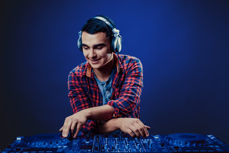 exicted dj sound device oprator with headphones by dancing at club - concept of entertainment, nightlife, music club and musicianの写真素材