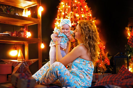 Mother and baby daughter having fun, playing together near Christmas tree in decorated living roomの写真素材