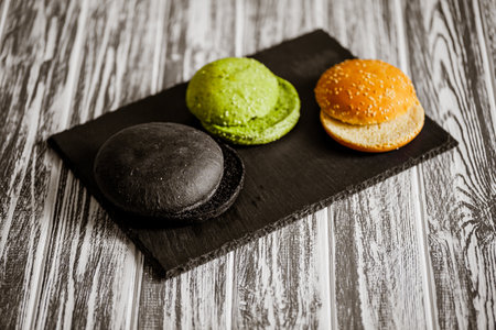 From above view of variety of three hamburger buns on wooden table. Black, green, yellow bunsの写真素材