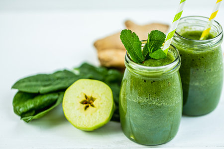 Glasses jars with straws filled with green smoothie and ingredients on wooden table. Vegetarian dietの写真素材