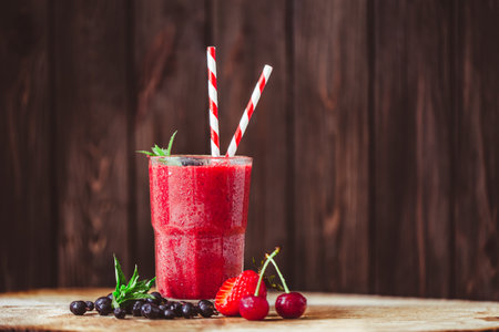 Front view of glass with fresh crimson smoothie with summer berries on wooden background. Good foodの写真素材