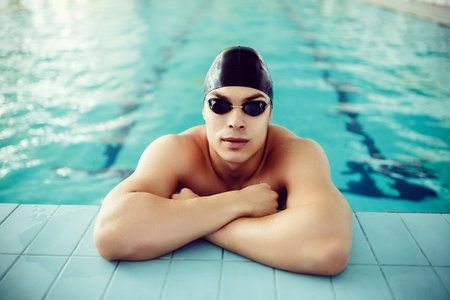 portrait of handsome professional swimmer on edge of the pool. Sport concept