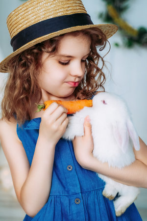 Portrait of cute little girl who holding and feeding rabbit carrot, learning to take care of animalsの写真素材