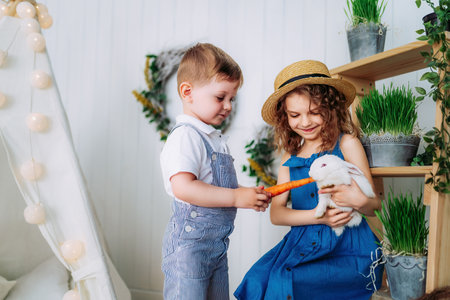 Children feeding white rabbit carrots indoor learning to take care of an animals. Happy childhoodの写真素材