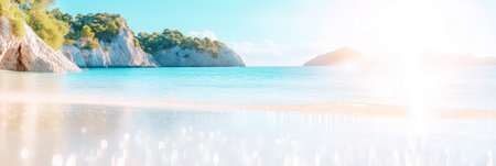 A serene coastal view captures a clean shoreline with gentle green hills rising in the background under a bright midday sun. The tranquil waters reflect the clear blue sky.の素材