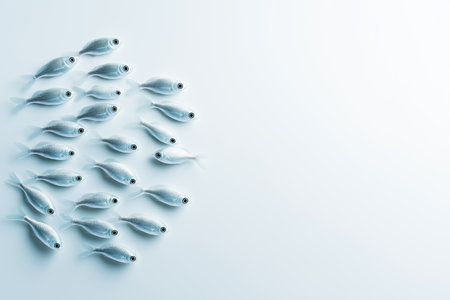 Small fish swimming in formation against a clean white background. Aquatic life setting creating peaceful ambiance. Concept of marine biology, aquaculture, environmental conservation.の素材