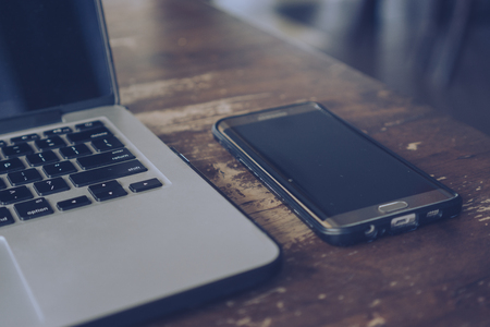Laptop and smartphone on wooden table.