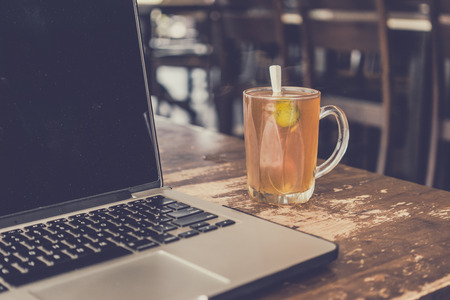 Hot tea and laptop on wooden table.の写真素材