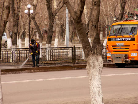 a car with the Russian inscription "disinfection" disinfects the streets of the city to protect against COVID-19のeditorial素材