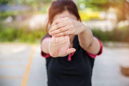 Women exercising. Young fitness woman exercising in sunny bright light in the morning. Closeup of woman stretching his hand, wrist, and forearm.の写真素材