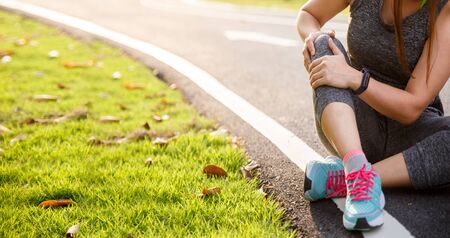 Female runner athlete knee injury and pain. Woman suffering from painful knee while running in the...