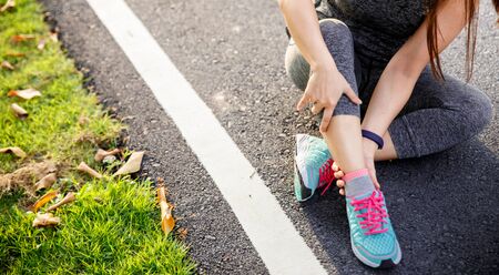 Female runner athlete leg injury and pain. Woman suffering from painful leg while running in the park.の写真素材