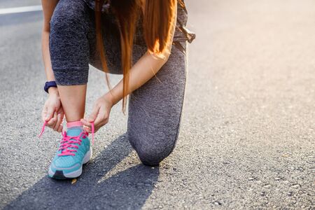 Woman runner tying running shoes before run for exercise in the morning. Woman runner checking shoe...