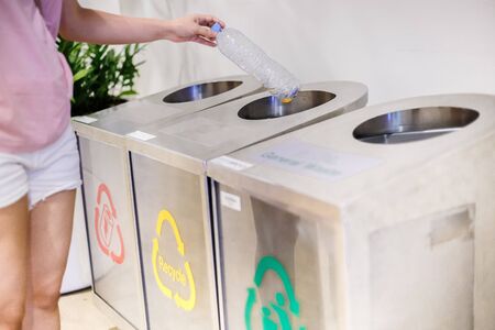 Woman using waste separation container throwing away garbage plastic. Different colored recycle...