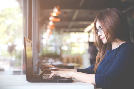 Beautiful young Asia woman working using computer or laptop and smiling, Young business woman working from home. Responding on business e-mail. Business concepts.の写真素材