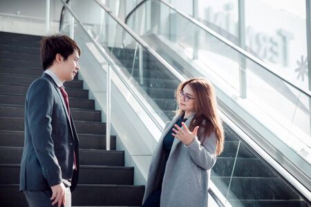 Two smiling diverse businesspeople standing together outside of their office complex during a break. Businessman talking with colleague.の写真素材