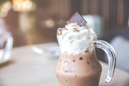 Iced cocoa drink with whipping cream topping on the wooden table in cafe.の写真素材