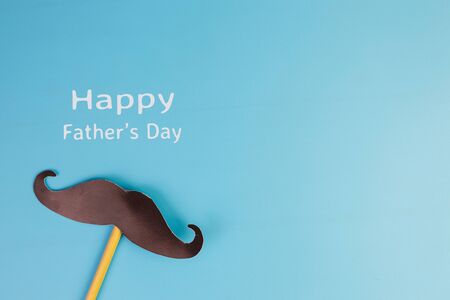 Happy Father's day concept. A black mustache pape and the text written that Happy Father's Day isolated on blue background.の写真素材