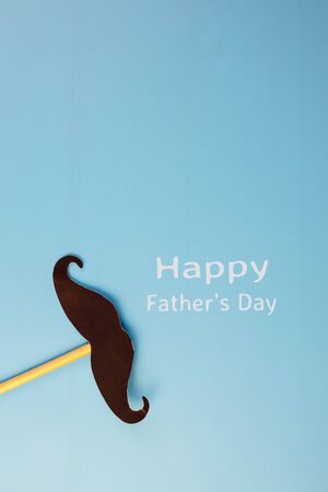 Happy Father's day concept. A black mustache pape and the text written that Happy Father's Day isolated on blue background.の写真素材