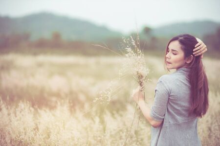Flowers and the woman palm in the field. Lit evening sun. Carefree Happy Woman Enjoying Nature on grass meadow on top of mountain cliff with sunrise. Beauty Girl Outdoor. Freedom concept.の写真素材