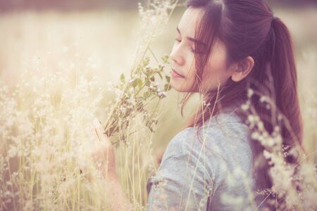 Flowers and the woman palm in the field. Lit evening sun. Carefree Happy Woman Enjoying Nature on grass meadow on top of mountain cliff with sunrise. Beauty Girl Outdoor. Freedom concept.の写真素材