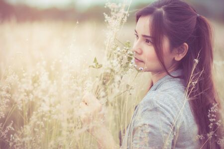 Flowers and the woman palm in the field. Lit evening sun. Carefree Happy Woman Enjoying Nature on grass meadow on top of mountain cliff with sunrise. Beauty Girl Outdoor. Freedom concept.の写真素材