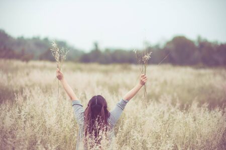 Flowers and the woman palm in the field. Lit evening sun. Carefree Happy Woman Enjoying Nature on grass meadow on top of mountain cliff with sunrise. Beauty Girl Outdoor. Freedom concept.の写真素材