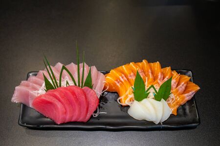 Close up fresh raw sasimi fish set  in a black dish on black table.の写真素材