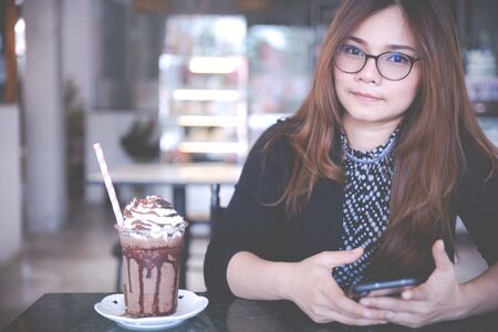 Beautiful woman and Summer refreshment drinks. Chilled iced chocolate cocoa. Chocolate powder and ice with tubes for drinking in the cafe. Copy space.の写真素材