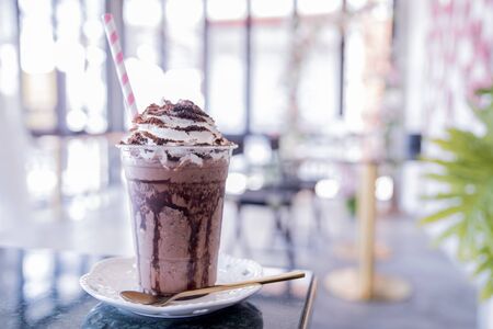 Summer refreshment drinks. Chilled iced chocolate cocoa. Chocolate powder and ice with tubes for drinking in the cafe. Copy space.の写真素材
