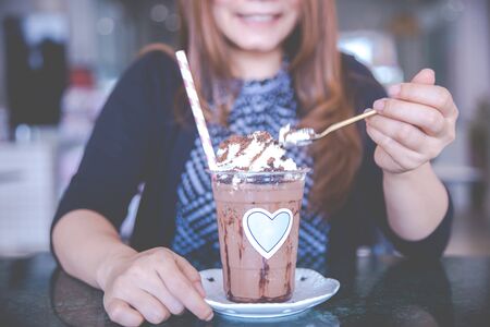 Beautiful woman and Summer refreshment drinks. Chilled iced chocolate cocoa. Chocolate powder and ice with tubes for drinking in the cafe. Copy space.の写真素材