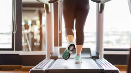 Close up foot sneakers Fitness girl running on track treadmill, Fat woman with muscular legs in...