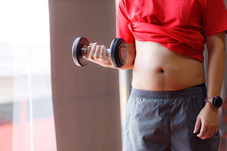 Fit young woman lifting barbells looking focused, working out in a gym.