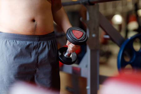 Fit young woman lifting barbells looking focused, working out in a gym.の写真素材