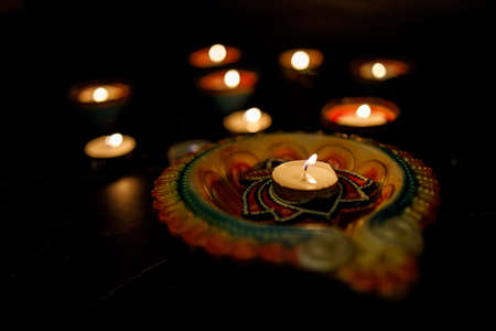 Happy Diwali - Clay Diya lamps lit during Dipavali with flowers, Hindu festival of lights celebration. Colorful traditional oil lamp diya on dark background. Copy space for text.の写真素材