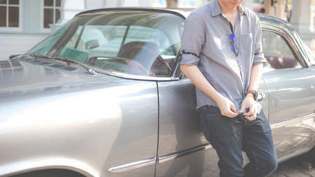 Young man standing near vintage car - concept of buying a used car or a rental car.