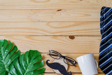 Blur of Background, Happy Father's day concept. A black mustache paper, a blue necktie, a blue gift box and glasses on wooden table.の写真素材
