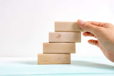 Hand arranging wood block stacking as step stair. Business concept for growth success process....