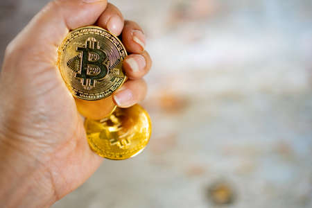 Close up one golden coin with the bitcoin symbol in hand. Young hand holding cryptocurrency coin, Money coins digital, BTC.の写真素材