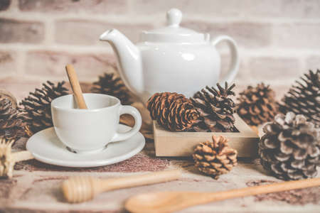 Tea concept, white teapot with white tea cup with dry leaves on wooden background, view from side. organic product from the nature for healthy with traditional.の写真素材