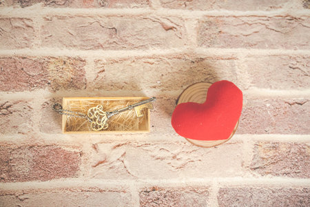 Bronze house key and red country fabric heart  old wood, Valentines Day, real estate and home concept background with wooden painted copy space.の写真素材