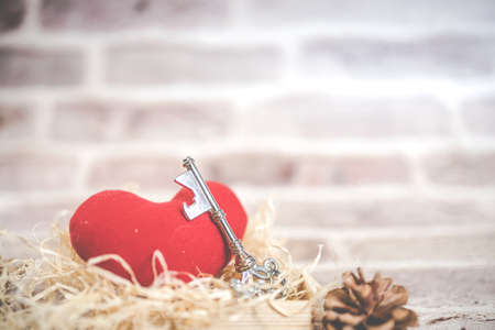 Bronze house key and red country fabric heart  old wood, Valentines Day, real estate and home concept background with wooden painted copy space.の写真素材