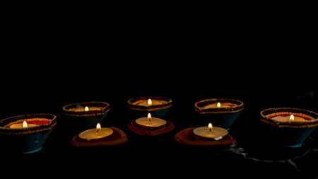 Happy Diwali - Clay Diya lamps lit during Dipavali, Hindu festival of lights celebration. Colorful traditional oil lamp diya on dark background. Copy space for text.の写真素材