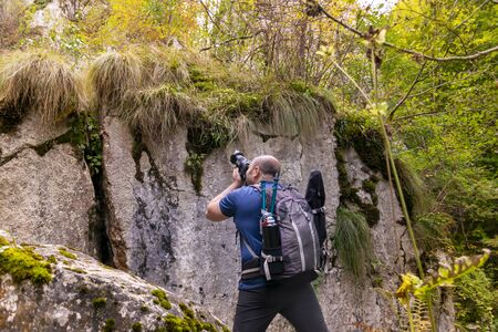 man tourist photographer with camera on a mountain outdoors during a hike in autumn