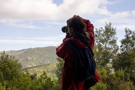 Woman tourist photographer with camera on a mountain outdoors during a hike in autumn